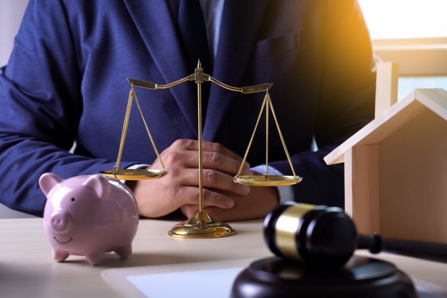 Attorney with scales, piggy bank, gavel, and house model