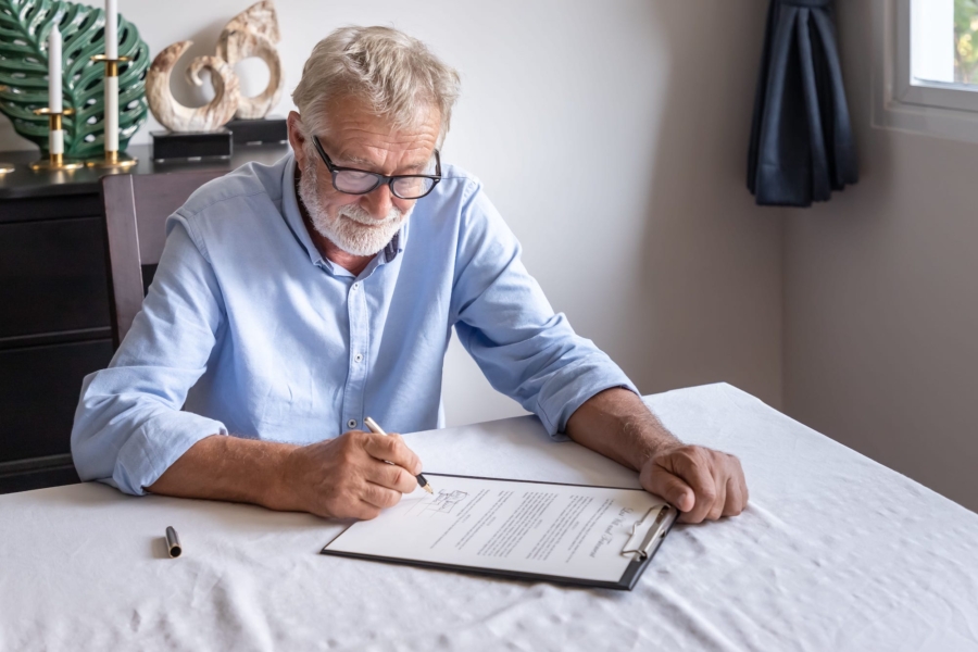 Senior man with clipboard signing document